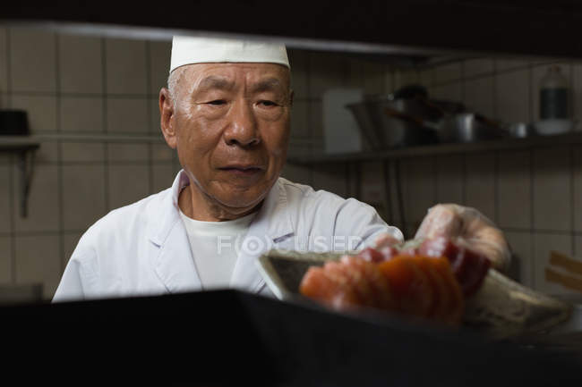 Старший повар готовит суши на кухне в отеле — стоковое фото
