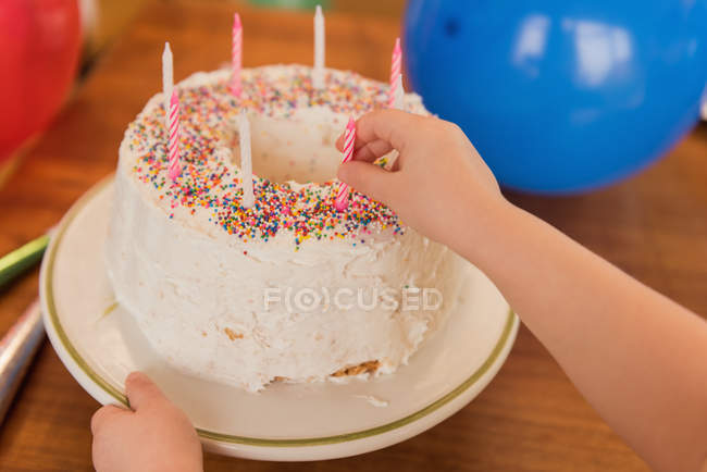 Close-up of girl putting candle on birthday cake — Stock Photo