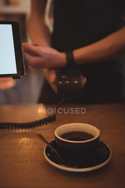 Cliente haciendo el pago con smartwatch en el mostrador en cafetería - foto de stock