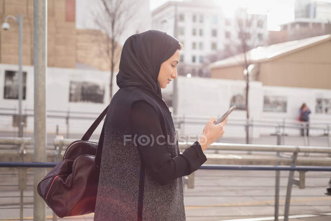 Mulher no hijab usando telefone celular em um dia ensolarado — Fotografia de Stock