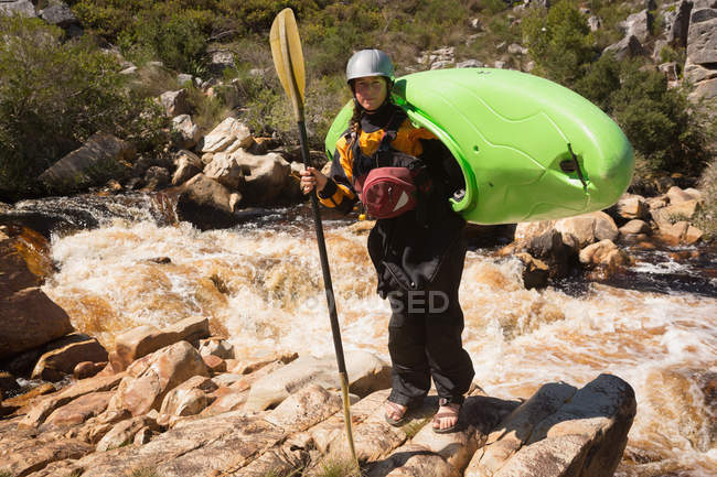 Femme debout avec kayak bateau et pagaie par la rivière . — Photo de stock