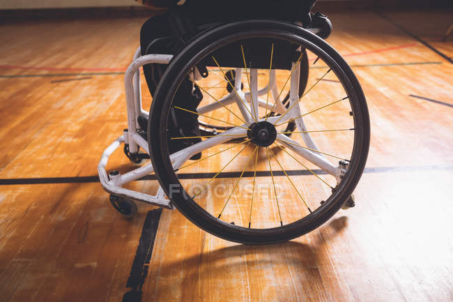 Sección baja del hombre discapacitado en silla de ruedas en la cancha de baloncesto - foto de stock