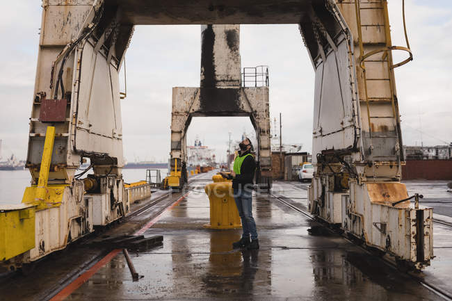 Dock worker inspecting the huge cranes in shipyard — Stock Photo