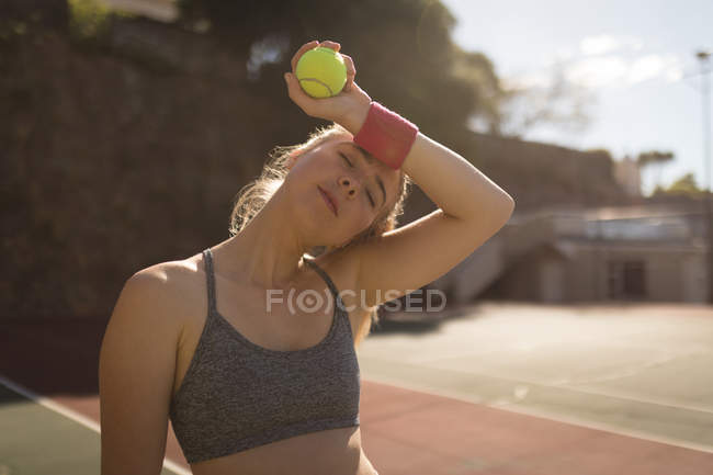 Frau schwitzt beim Tennisspielen auf dem Tennisplatz an einem sonnigen Tag — Stockfoto