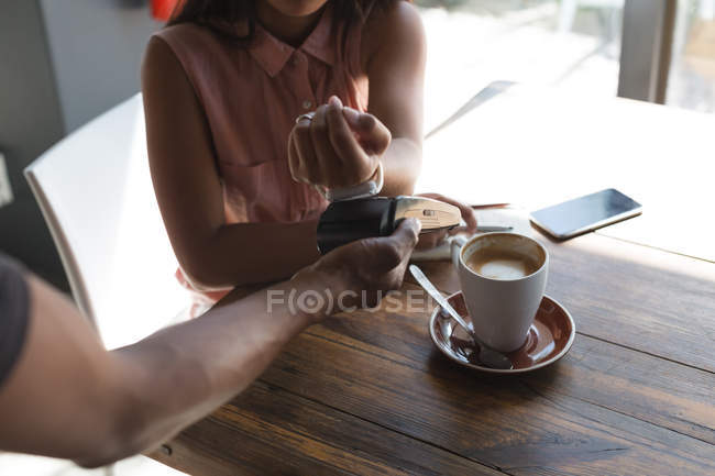 Teenage girl making payment through smartwatch — Stock Photo