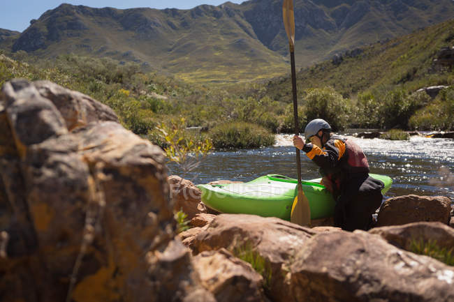Mujer caminando con bote de kayak y remo a río . - foto de stock