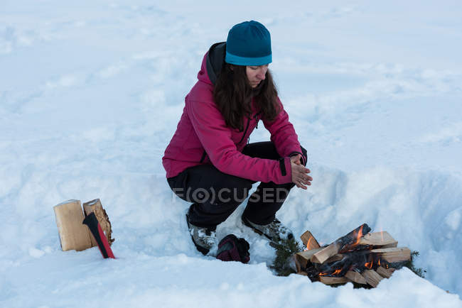 Female tourist warming up by bonfire during winter. — Stock Photo