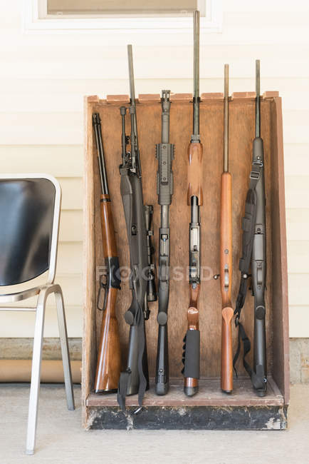 Various guns arranged in wooden rack on a sunny day — Stock Photo