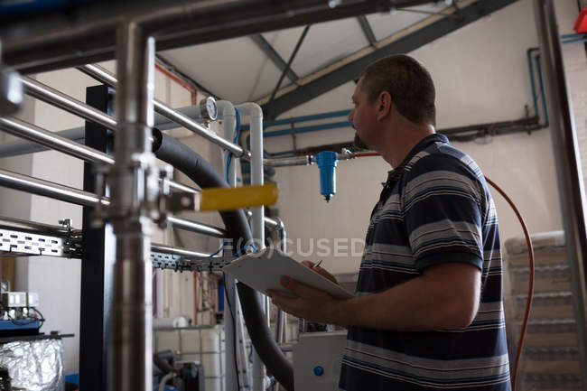 Работник мужского пола контролирует манометр резервуара для хранения на джине — стоковое фото