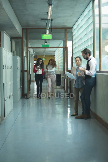Executives discussing with each other at office corridor — Stock Photo
