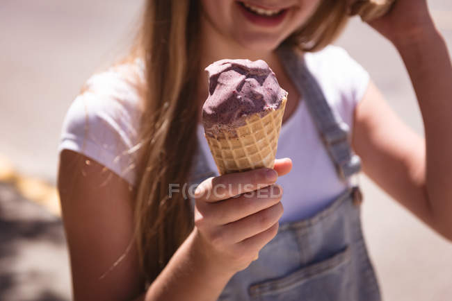 Gros plan de la fille tenant un cône de gaufre avec de la crème glacée à l'extérieur . — Photo de stock