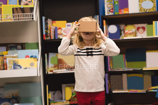 Девушка притворяется, что пользуется гарнитурой виртуальной реальности в книжном магазине — стоковое фото