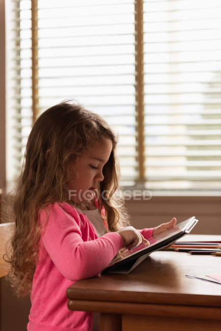 Linda chica usando tableta digital en casa - foto de stock
