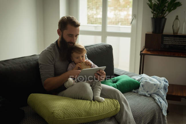 Padre e hijo usando tableta digital en casa - foto de stock