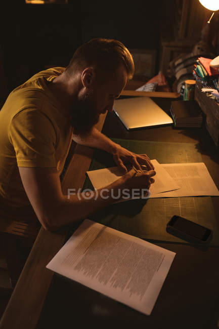 Человек, сидящий на стуле и пишущий письмо дома — стоковое фото