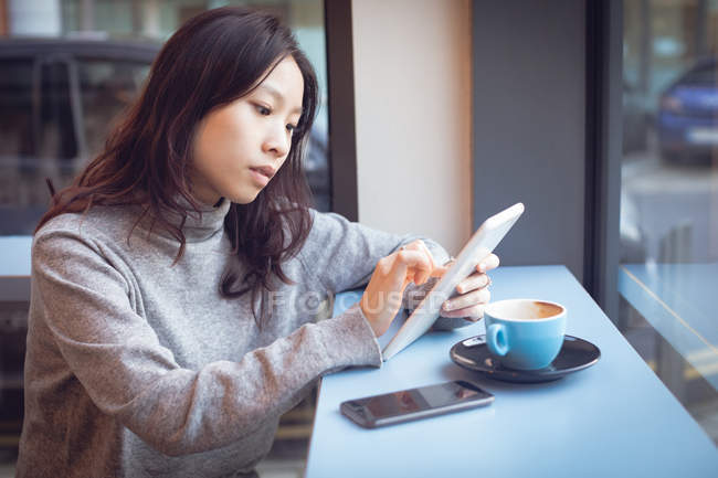 Красива жінка, використовуючи цифровий планшетний маючи кави в кафетерії — стокове фото