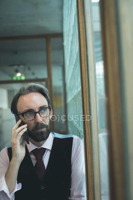 Exécutif parlant sur téléphone portable dans le couloir de bureau — Photo de stock