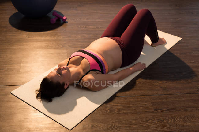 Femme enceinte effectuant du yoga dans le salon — Photo de stock