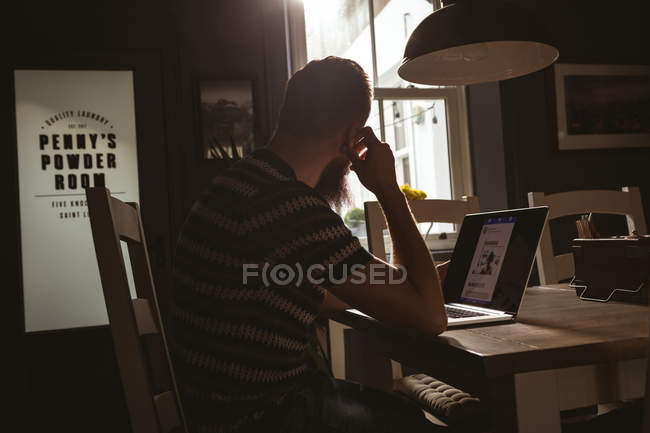 Чоловік сидить на стільці, використовуючи свій ноутбук вдома — стокове фото