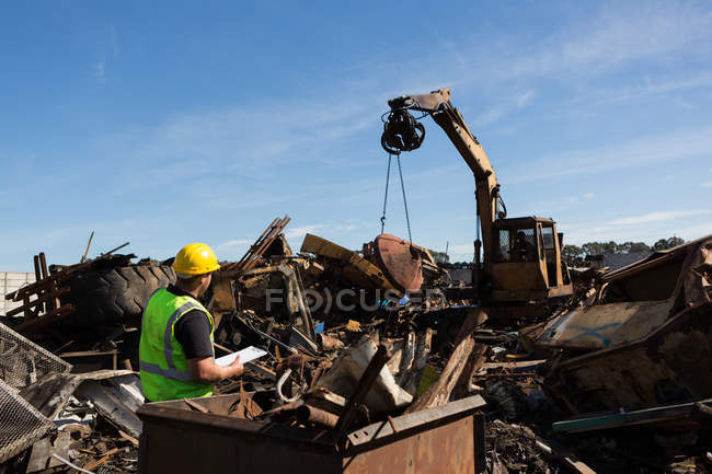 Вид ззаду працівника, який стежить за сміттям, піднятим краном — стокове фото