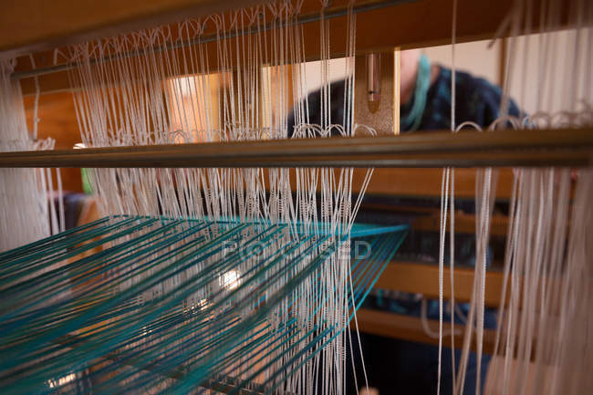 Mid section of senior woman weaving silk at shop — Stock Photo