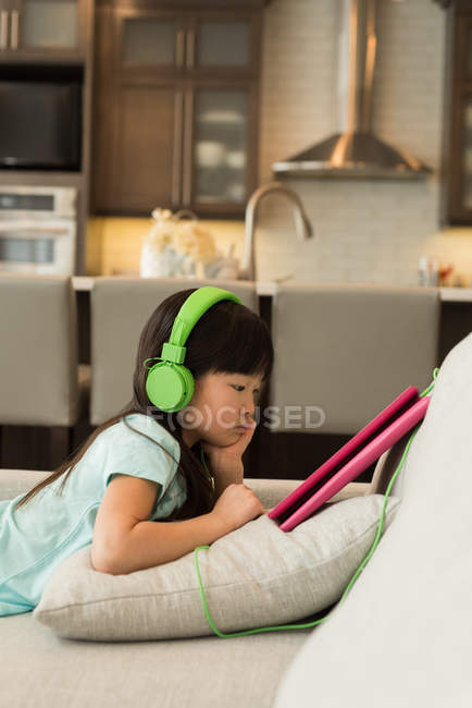 Woman with headphones using digital tablet at home — Stock Photo