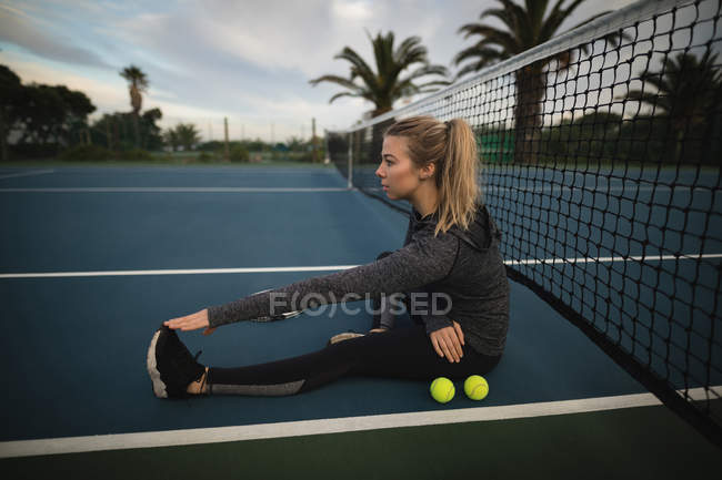 Jovem realizando exercícios de alongamento na quadra de tênis — Fotografia de Stock