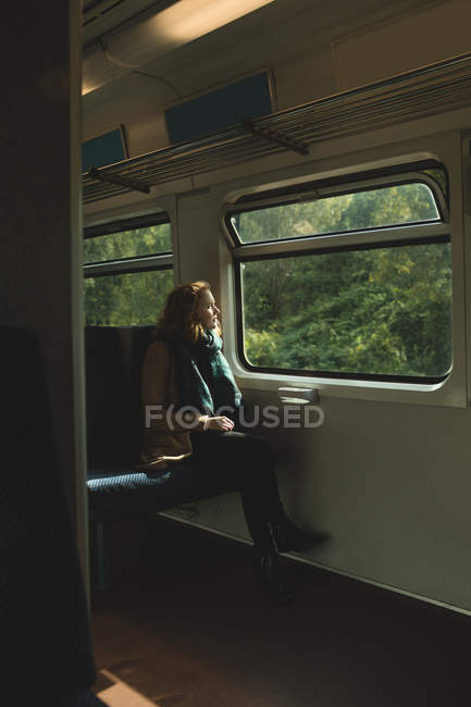 Jeune femme réfléchie voyageant en train — Photo de stock