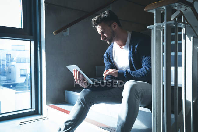 Executives using laptop on stairs in modern office — Stock Photo