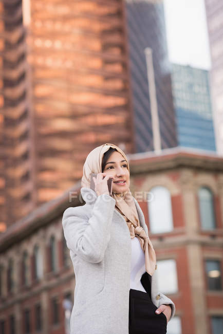 Женщина в хиджабе разговаривает по мобильному телефону в городе — стоковое фото