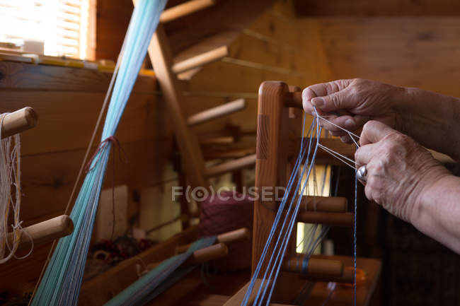 Nahaufnahme einer Seniorin beim Seidenweben im Geschäft — Stockfoto
