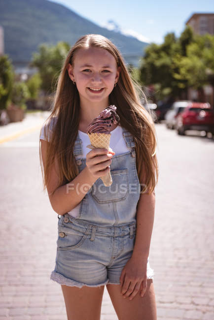 Вид спереду дівчини з морозивом, що стоїть на дорозі в місті . — стокове фото