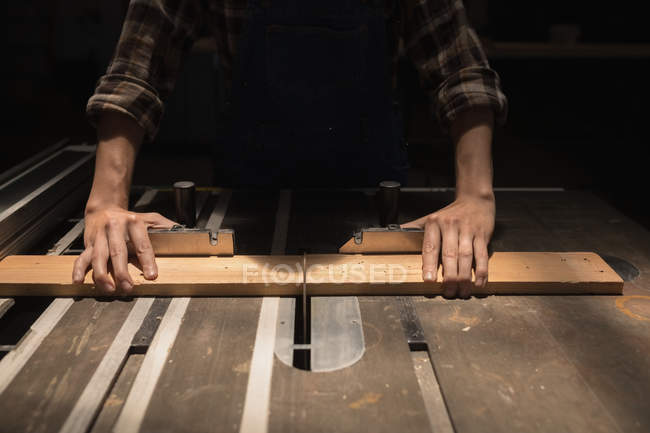 Mid section of female artisan measuring wooden piece in workshop. — Stock Photo