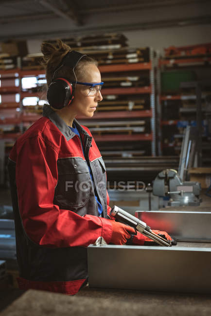 Trabalhadora do sexo feminino reparar uma máquina com ferramenta na fábrica — Fotografia de Stock