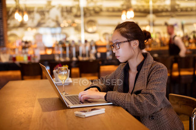 Female executive using laptop at table in hotel — Stock Photo