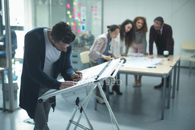 Male executive working over drafting table in office — Stock Photo