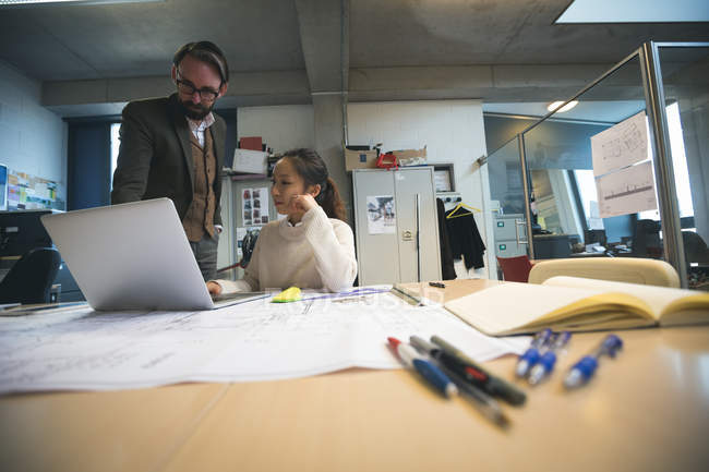 Executivos discutindo sobre laptop no escritório moderno — Fotografia de Stock