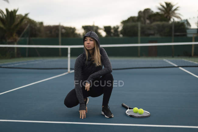 Задумчивая женщина на теннисном корте — стоковое фото