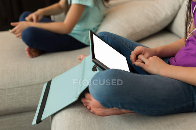 Frères et sœurs utilisant une tablette numérique dans le salon à la maison — Photo de stock