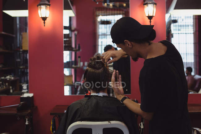 Man getting his hair trimmed with scissor at barbershop — Stock Photo