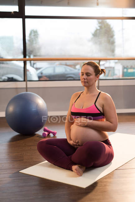 Беременная женщина медитирует, прикасаясь к животу — стоковое фото
