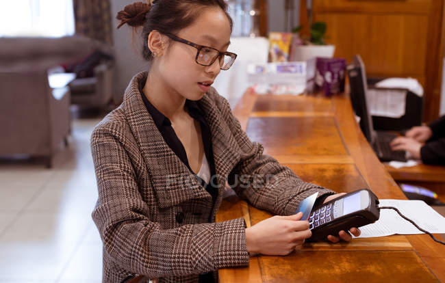 Femme cadre glissant sa carte sur le terminal de paiement à la réception — Photo de stock