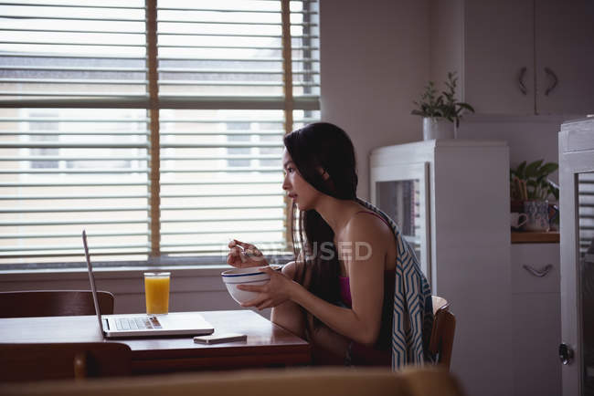 Donna che fa colazione sul tavolo da pranzo a casa — Foto stock