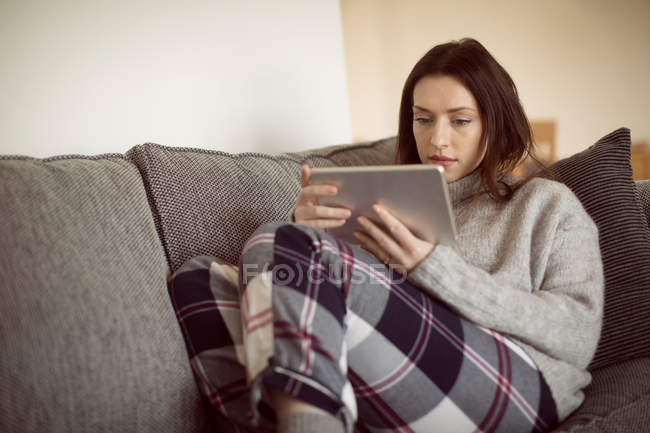 Frau nutzt digitales Tablet auf Sofa im heimischen Wohnzimmer. — Stockfoto