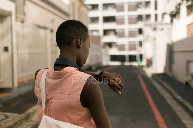 Rückansicht einer Frau, die auf ihrer Wache in der Stadtstraße die Uhrzeit kontrolliert — Stockfoto