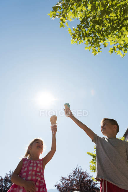 Siblings holding ice cream against sky on a sunny day — Stock Photo
