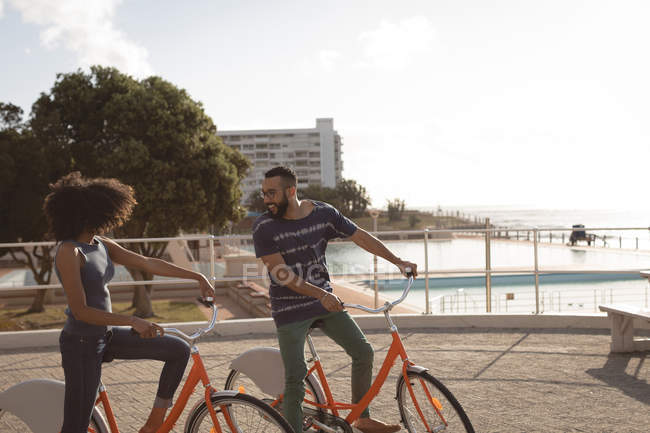 Пара, смотрящая друг на друга, наслаждаясь велосипедной прогулкой в солнечный день — стоковое фото