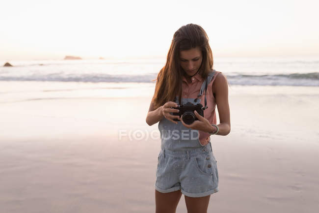 Woman holding camera in beach at dusk. — Stock Photo