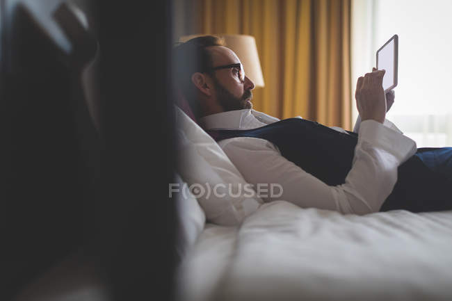 Homme d'affaires utilisant une tablette numérique dans la chambre à coucher à l'hôtel — Photo de stock