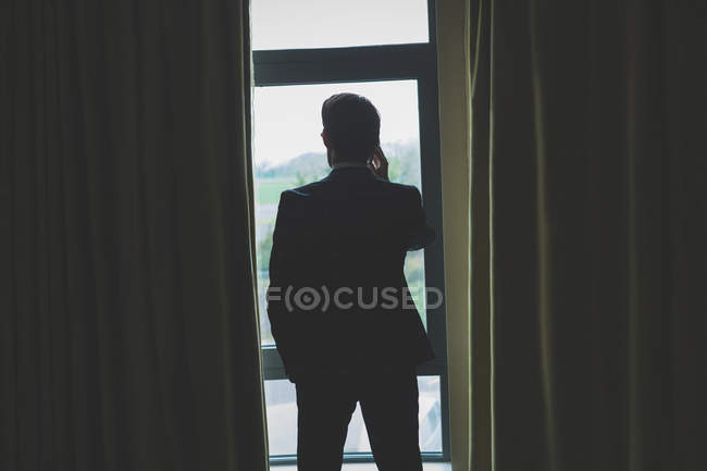 Visão traseira do homem de negócios falando no telefone celular no quarto de hotel — Fotografia de Stock